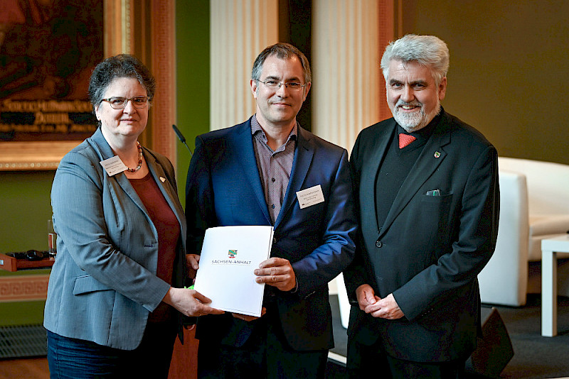 Rektorin Claudia Becker und Jonathan Everts erhalten den Förderbescheid von Minister Armin Willingmann (von links).